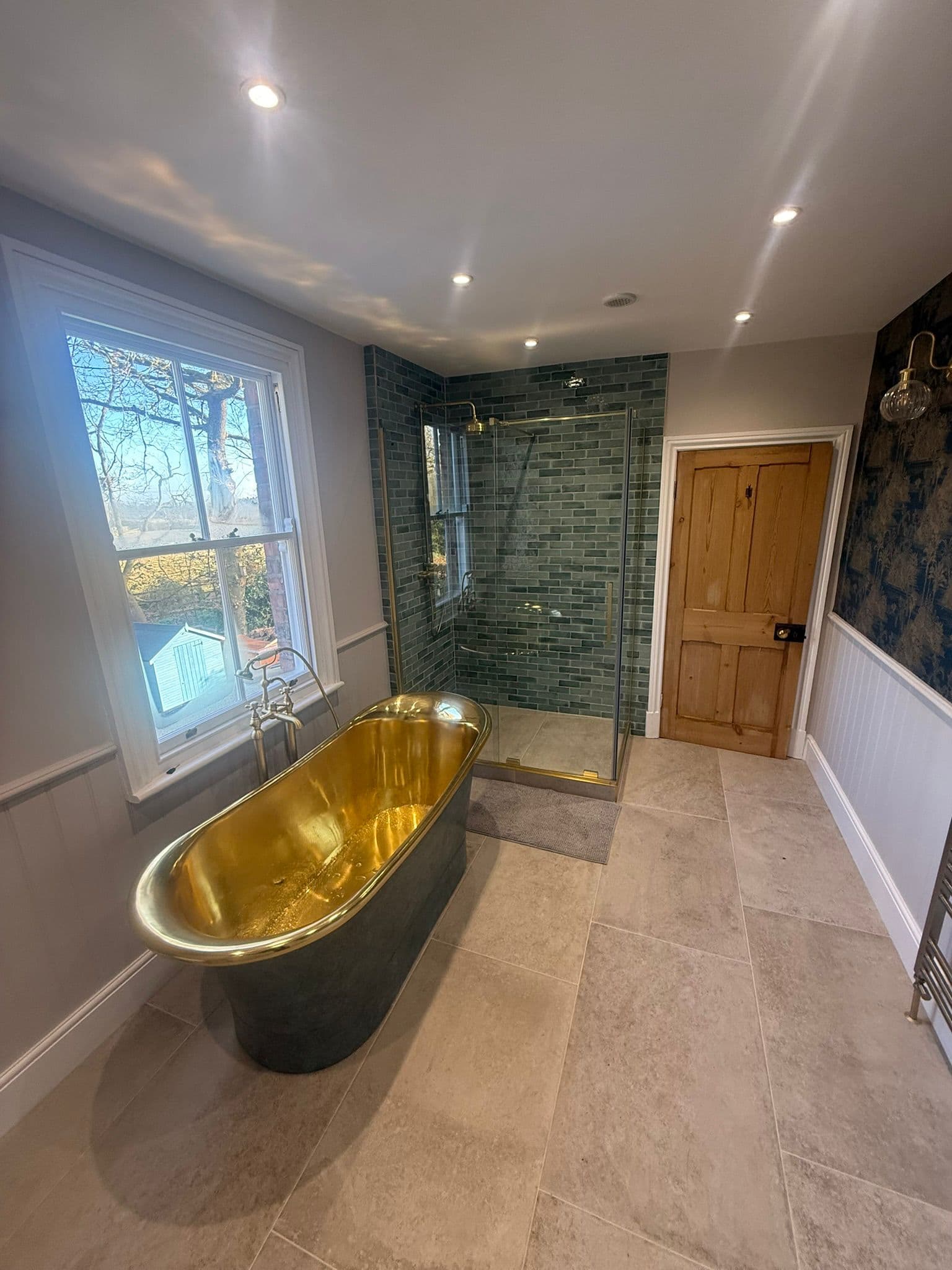 Statement brass bathroom in Ranby with green shower tiling and tiled floor