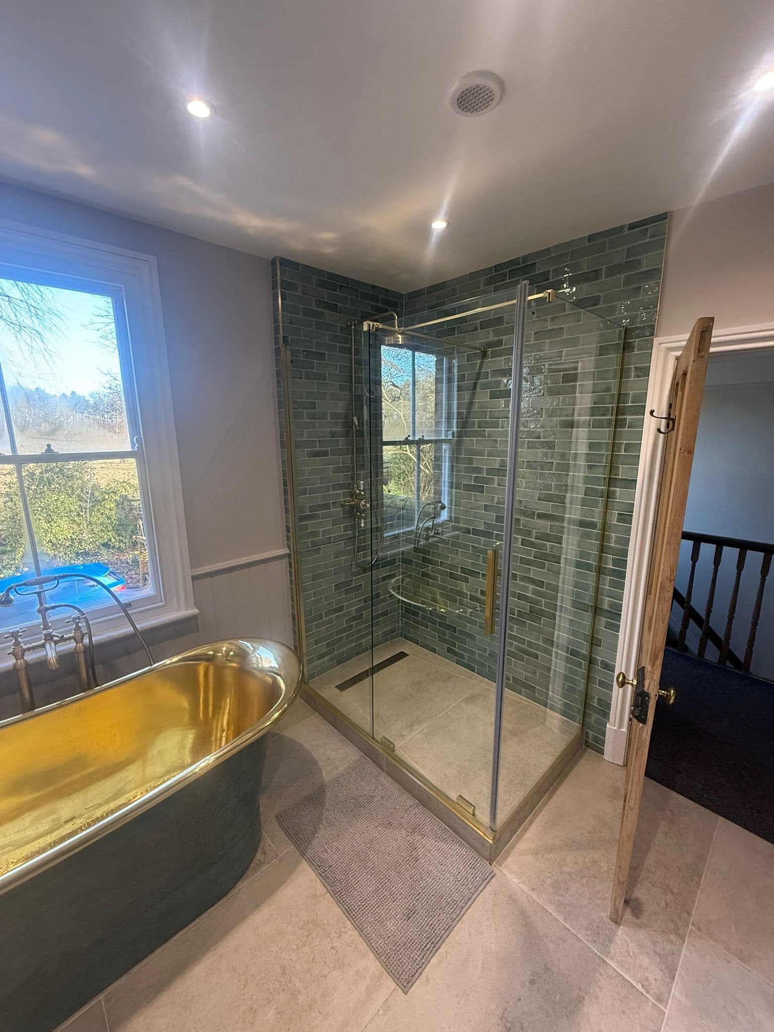 Statement brass bathroom in Ranby with green shower tiling and tiled floor