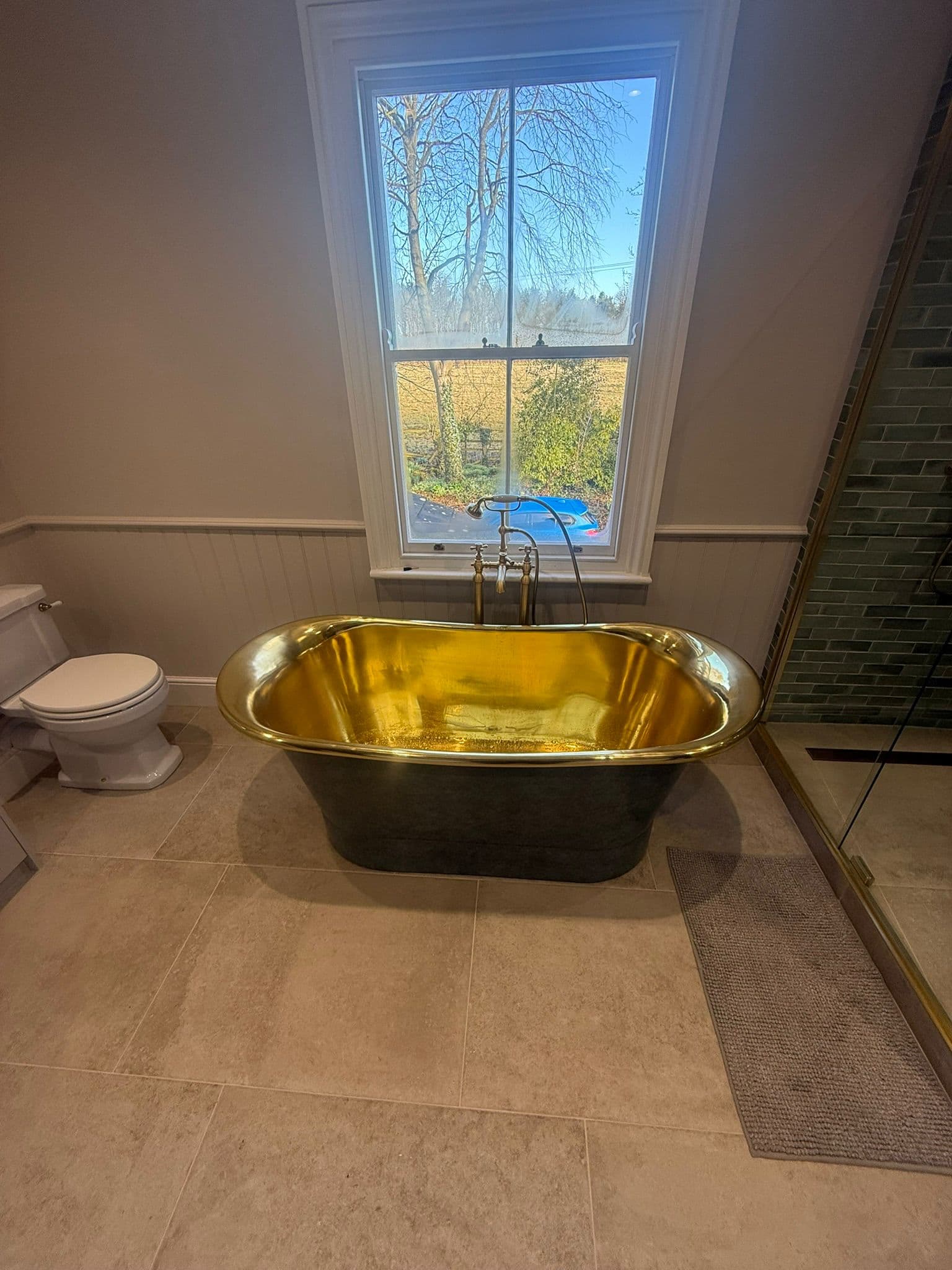 Statement brass bathroom in Ranby with green shower tiling and tiled floor